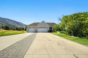 Ranch-style house with an attached garage, driveway, a front lawn, and stucco siding