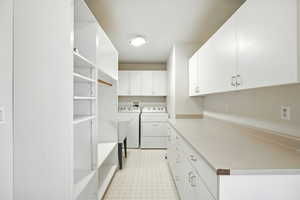 Laundry area featuring light flooring, cabinet space, and washer and clothes dryer