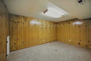 Carpeted spare room with wooden walls
