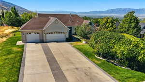 View of front of property with an attached garage, a mountain view, roof with shingles, and stucco siding