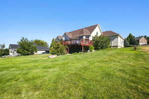 Rear view of house featuring a wooden deck and a lawn