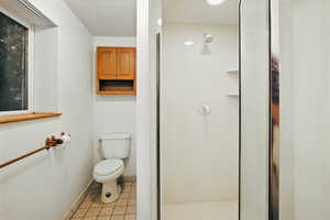 Full bath featuring light tile patterned floors and a shower stall