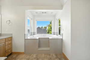 Bathroom with vanity, a garden tub, dark wood finished floors, and healthy amount of natural light