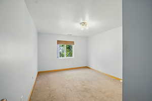 Empty room featuring light carpet and a textured ceiling