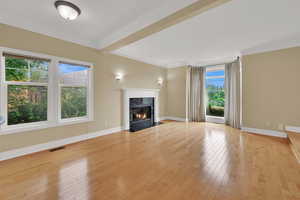 Unfurnished living room with ornamental molding, a fireplace, and light wood-style floors