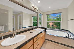 Bathroom with ornamental molding, double vanity, a garden tub, light tile patterned floors, and recessed lighting