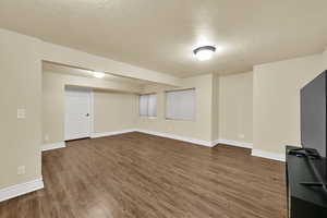 Finished below grade area with dark wood-type flooring and a textured ceiling