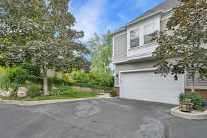 View of side of property featuring brick siding, a garage, and driveway