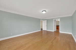 Unfurnished bedroom featuring ornamental molding, light wood-style floors, and connected bathroom