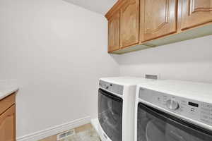 Washroom featuring cabinet space, washer and dryer, and light tile patterned floors