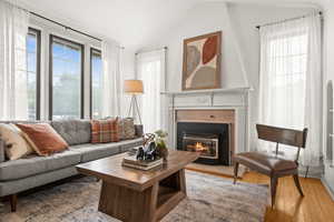 Living room with vaulted ceiling, a fireplace with flush hearth, and light wood-type flooring