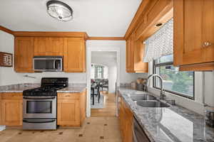 Kitchen featuring appliances with stainless steel finishes, light stone countertops, plenty of natural light, and ornamental molding
