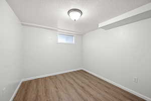 Unfurnished room with wood finished floors and a textured ceiling