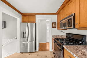 Kitchen featuring stainless steel appliances, brown cabinets, and light tile patterned floors