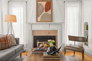 Living area featuring wood finished floors, a lit fireplace, and healthy amount of natural light