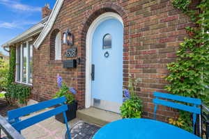 View of exterior entry featuring brick siding and a chimney