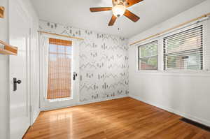 Spare room featuring wallpapered walls, light wood-style flooring, and ceiling fan