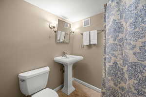 Full bath with a textured ceiling, light tile patterned floors, and a shower with curtain