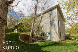 Back of house with a lawn and a shed