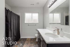 Bathroom with dark stone finish flooring, vanity, and a shower with shower curtain