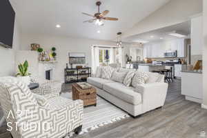 Living area with recessed lighting, vaulted ceiling, a fireplace, a ceiling fan, and new LPV floors