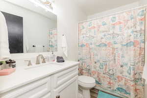 Full bath featuring vanity, curtained shower, and wood finished floors
