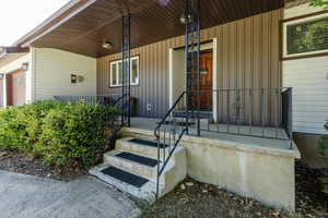 Property entrance with board and batten siding, covered porch, and a garage