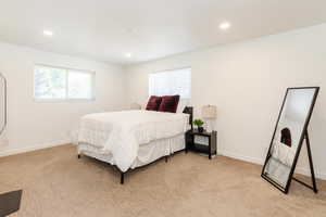 Bedroom with multiple windows, light colored carpet, and recessed lighting
