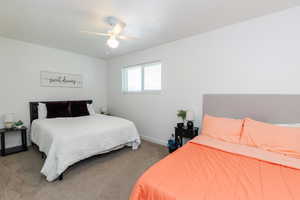 Carpeted bedroom featuring a ceiling fan and baseboards
