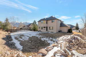 Snow covered rear of property featuring a fenced backyard, stucco siding, and a patio