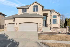 View of front of house featuring roof with shingles, stone siding, and stucco siding