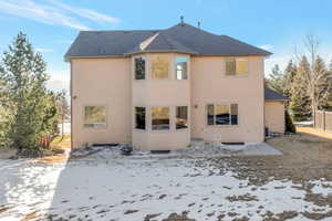 Snow covered house featuring a shingled roof, a patio, stucco siding, and crawl space