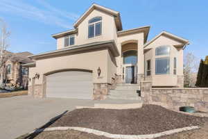 View of front of house with stone siding, stucco siding, and concrete driveway