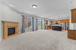 Unfurnished living room featuring a chandelier, recessed lighting, a fireplace, and light carpet