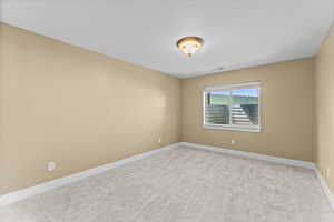 Carpeted spare room featuring baseboards and a textured ceiling