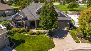 View of front of house with stone siding, driveway, roof with shingles, a garage, and a residential view