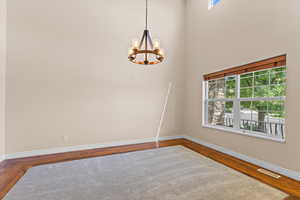 Unfurnished room featuring wood finished floors, a chandelier, and a towering ceiling
