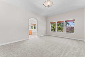 Spare room featuring light colored carpet and arched walkways