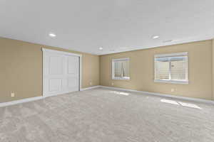 Unfurnished bedroom with carpet flooring, a closet, recessed lighting, and a textured ceiling