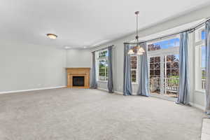 Unfurnished living room with a glass covered fireplace and light colored carpet