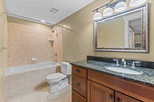 Bathroom featuring tiled shower / bath, vanity, and light tile patterned floors