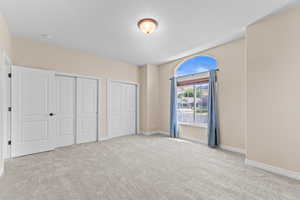 Unfurnished bedroom featuring light colored carpet and baseboards