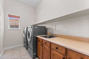 Laundry room featuring independent washer and dryer, light tile patterned floors, and cabinet space