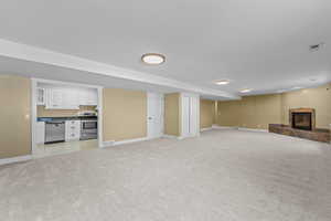 Unfurnished living room featuring a tile fireplace and light carpet