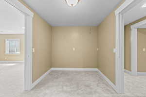 Empty room featuring light carpet and a textured ceiling