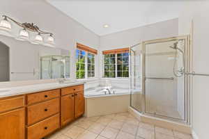 Full bath featuring a stall shower, light tile patterned floors, double vanity, a bath, and recessed lighting