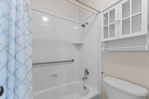 Full bathroom with shower / tub combo with curtain and toilet