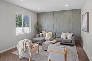 Living area featuring carpet, recessed lighting, and a decorative wall
