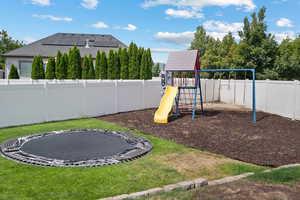 Communal playground featuring a trampoline and a fenced backyard