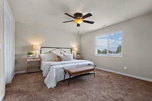 Bedroom with carpet floors, ceiling fan, and a textured ceiling